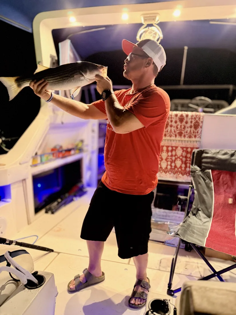 Captain Rob kissing a Lake Lanier striped bass on the boat at night